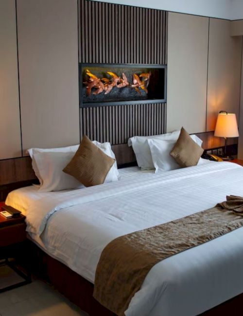 A hotel room with a king-sized bed, two bedside lamps, decorative pillows, and a window with curtains.