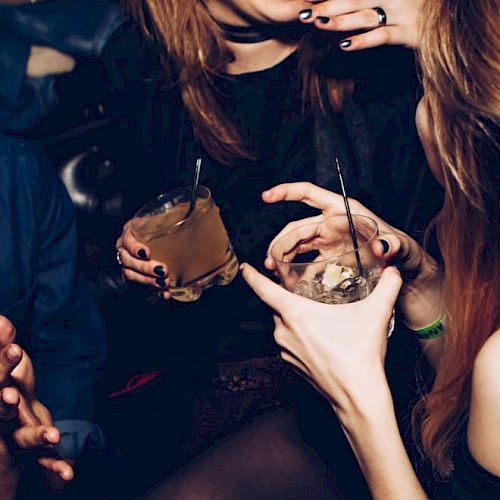 People enjoying drinks and socializing in a lively setting, with a focus on the drinks and interaction.