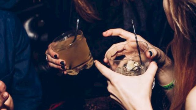 People enjoying drinks and socializing in a lively setting, with a focus on the drinks and interaction.