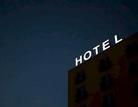 A building sign reads "HOTEL" at night, with an unlit "L" against a dark sky.
