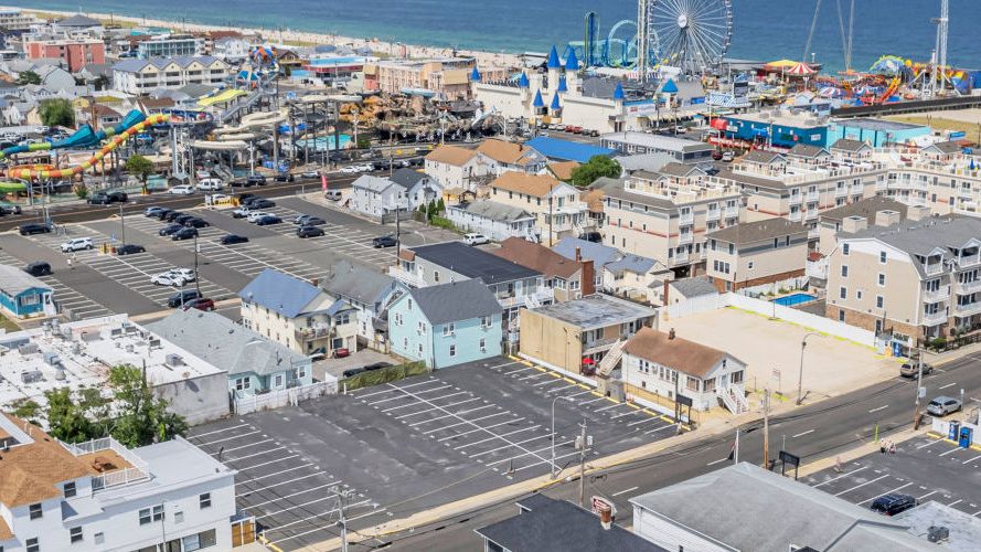 Aerial view of a coastal town featuring a beach, amusement park, and residential areas near the ocean.