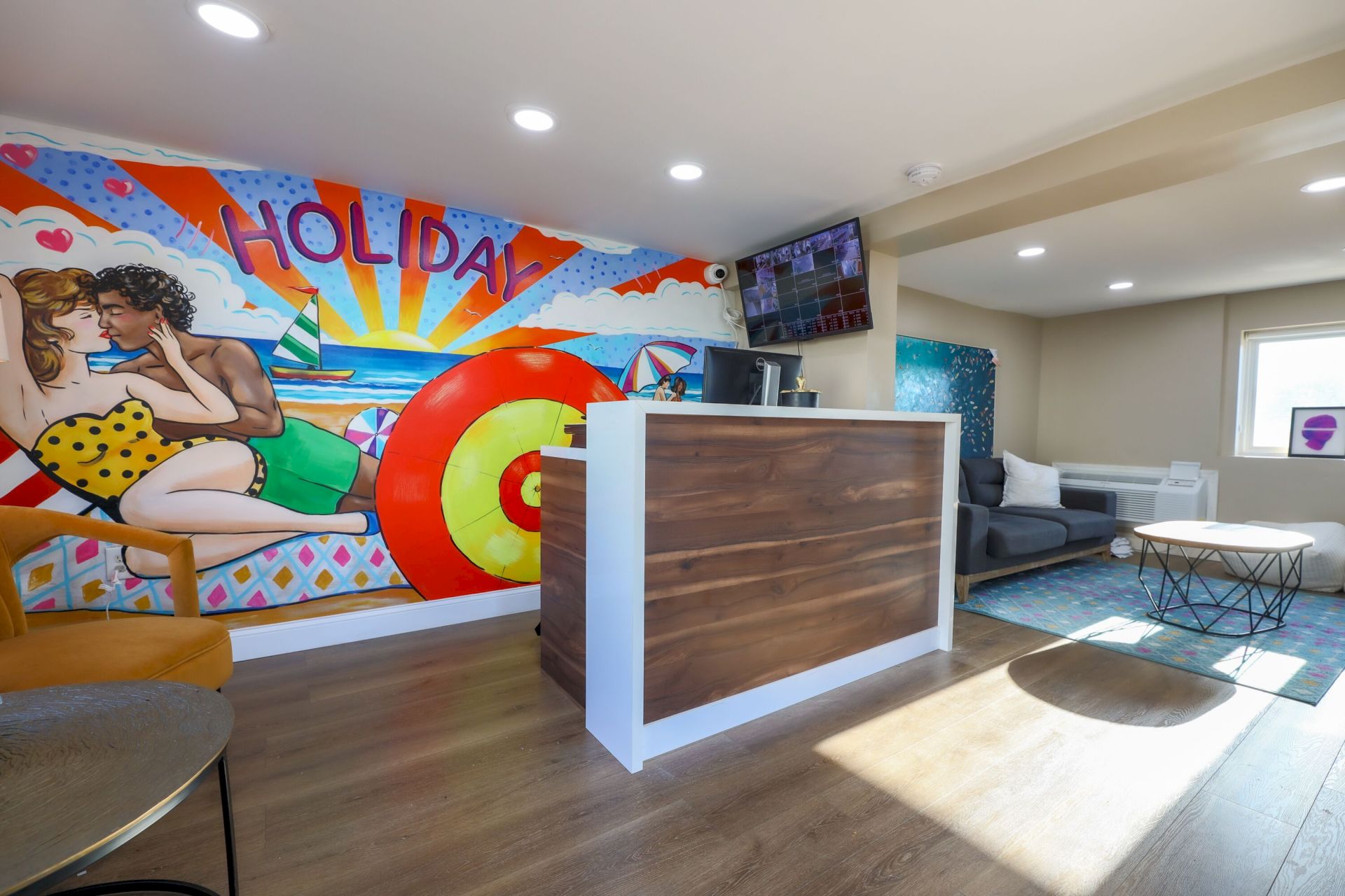 A vibrant room with a colorful wall mural, a modern reception desk, and cozy seating, creating a welcoming atmosphere.