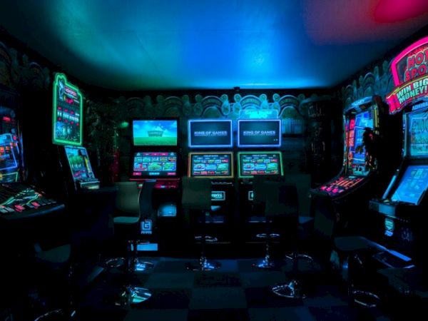 The image shows a dimly lit arcade with various gaming machines and colorful neon lights creating a vibrant atmosphere.