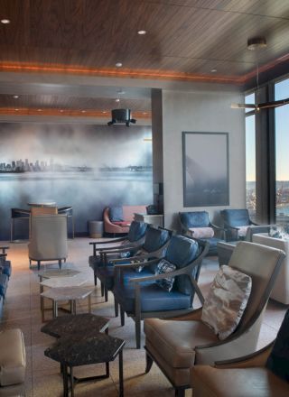 A modern lounge area with comfortable seating, large windows offering a scenic view of the water and Ferris wheel, and a stylish wall mural.